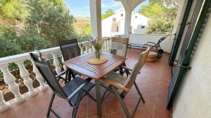 a porch with a wooden table and chairs on a balcony at Rose Wind Apartments by Pag tours in Pag