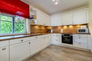 a white kitchen with white cabinets and a window at Villa Agni in Dänschendorf