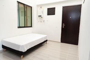 a white room with a bed and a black door at La camelia in Jardin