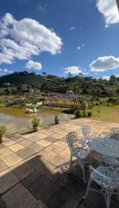 a patio with tables and chairs next to a river at Sítio do Vovô Adão in Domingos Martins