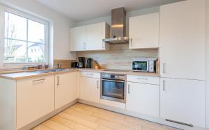 a white kitchen with white cabinets and a window at Seeigel in Zingst