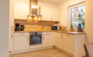 a kitchen with white cabinets and a window at Seewolf in Zingst