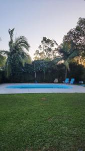 a swimming pool with two chairs and palm trees at Recanto da paz in Viamão