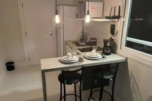 a small kitchen with a counter with two stools at Vista Para o Mar no 8º Andar conforto e Charme 807 in Salvador