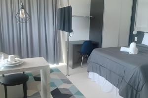 a bedroom with a bed and a table and a chair at Vista Para o Mar no 8º Andar conforto e Charme 807 in Salvador