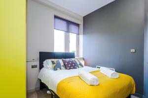 a bedroom with a yellow bed with a window at Stylish 2 Bedroom Apartment in Central Wigan by MDGC Developments Ideal For Weekends Away and Business Guests in Wigan