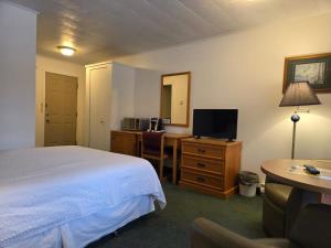 a hotel room with a bed and a desk with a television at Valois Motel & Restaurant in Mattawa