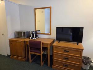 a room with a desk with a television and a mirror at Valois Motel & Restaurant in Mattawa