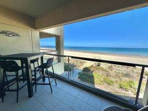 a balcony with a table and chairs and a view of the beach at Absolute Beachfront at the Pier Glenelg in Adelaide