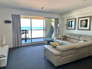 a living room with a couch and a view of the ocean at Absolute Beachfront at the Pier Glenelg in Adelaide