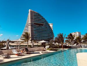 a hotel with a swimming pool and a tall building at Marina Corazón Sea View - Condo Puerto Cancún in Cancún