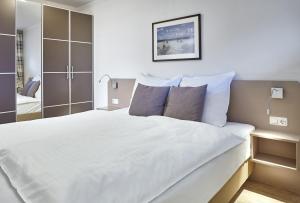 een slaapkamer met een groot bed met witte lakens en kussens bij STRANDIDYLL, 12 - Typ A2S in Grömitz