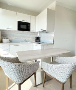 een keuken met witte kasten en een tafel en stoelen bij STRANDIDYLL, 23 - Typ A1S in Grömitz