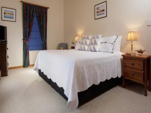 a bedroom with a white bed with a dresser and a window at Ambience on Huon Bed & Breakfast in Cygnet