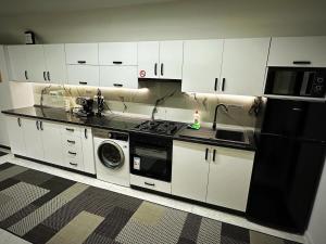 a kitchen with white cabinets and a black refrigerator at Apartament cu 2 Dormitoare de lux situat in complex ApartHotel Botosani 1 in Botoşani