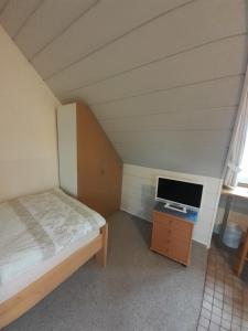 Un pequeño dormitorio con una cama y un televisor. en Appartement Klahn Nr2, en Fehmarn