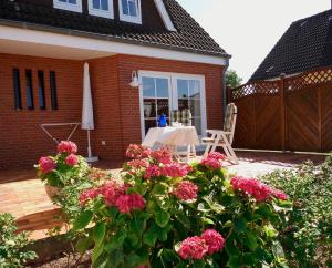 un patio con una mesa y flores frente a una casa en Appartement Klahn Nr1, en Fehmarn