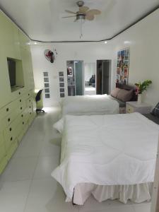 a white bedroom with two beds and a television at Room Calapan in Camilmil +26 photos