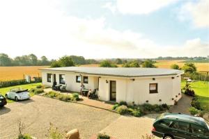 ein weißes Haus mit in einer Einfahrt geparkten Autos in der Unterkunft "Ferienhof Alte Mühle" W 1a in Bannesdorf + 4 Fotos