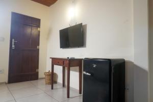a black refrigerator in a room with a table and a television at Pousada Solar D Alcina in Paraty