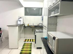 a small white kitchen with a yellow and black stripe on the floor at Apartamento Familiar em Capitólio in Capitólio