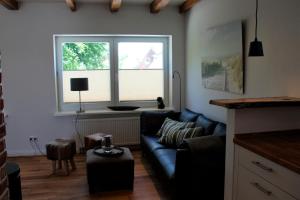 a living room with a blue couch and a window at Bachstelze in Neue Tiefe Fehmarn