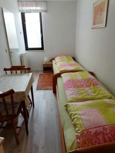 zwei Betten in einem Zimmer mit Tisch und Fenster in der Unterkunft Ferienwohnung Schattschneider in Burgtiefe auf Fehmarn 
