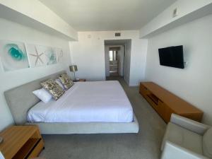 a bedroom with a white bed and a flat screen tv at Apt Miami Beach 1B1B with Kitchen Beach and Mall 2308 in Hallandale Beach +29 photos