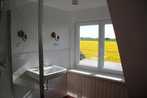 ein weißes Badezimmer mit Waschbecken und Fenster in der Unterkunft "Ferienhaus Strandläufer" in Neue Tiefe Fehmarn