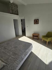 a bedroom with a bed and a green chair at Appartement au centre de Gosier 7 in Le Gosier