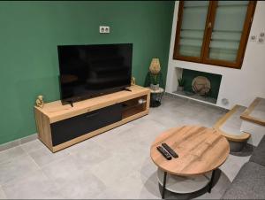 a living room with a flat screen tv and a table at Maison village in Sérignan