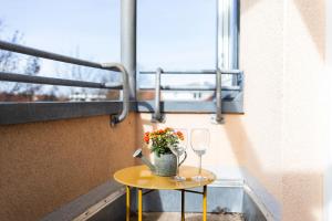 a table with a vase of flowers and a wine glass at Charmantes Apartment mit Tiefgarage in Magdeburg