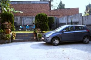 a small blue car parked in front of a house at The Serenity Space in Pātan