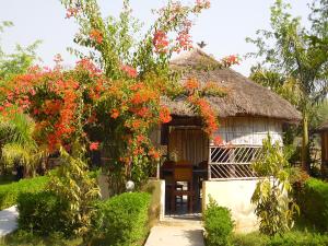 a house with a thatch roof with red flowers at Bardia Kingfisher Resort in Bardiyā