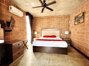 a brick walled bedroom with a bed and a ceiling fan at Vistas Increíbles frente al mar by G P S rentas in Mazatlán