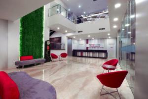 a lobby with red chairs and a green wall at favehotel Pekanbaru in Pekanbaru
