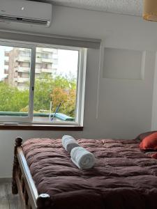 a bed with two towels on it in front of a window at 25 de Mayo Apart in Mendoza +5 photos