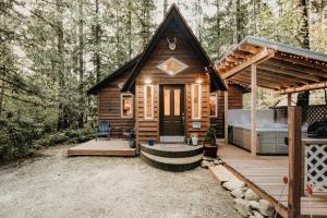 a cabin in the woods with a bed on a deck at Glacier Springs Cabin #16 - Hot Tub - Wi-Fi in Glacier