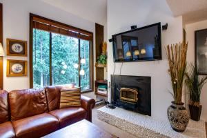 ein Wohnzimmer mit einem Ledersofa und einem Kamin in der Unterkunft Snowater Condo #31 - Fireplace - Wifi - Sleeps 4 in Glacier