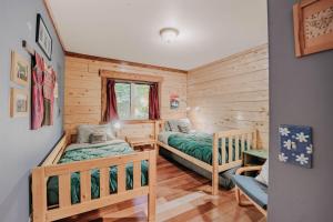 zwei Betten in einem Zimmer mit Holzwänden in der Unterkunft Glacier Springs Cabin #21 - Log Cabin - Wi-Fi - Pets Ok in Glacier