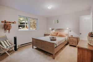 a bedroom with a bed and a chair and a window at Glacier Springs Cabin #30 - Hot Tub - Wi-Fi - Pets Ok in Glacier
