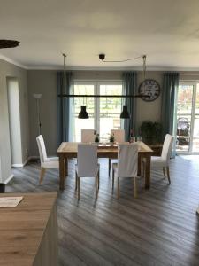 ein Esszimmer mit einem Holztisch und weißen Stühlen in der Unterkunft Ferienhaus Mau in Meeschendorf