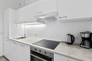 a white kitchen with a sink and a stove at Fast Wifi I 4 min to U3 Zipperer Straße in Vienna +37 photos
