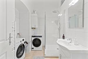 a white bathroom with a washing machine and a sink at Fast Wifi I 4 min to U3 Zipperer Straße in Vienna