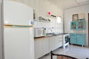 a kitchen with white cabinets and a white refrigerator at Contêiner Exclusivo - Praia da Gamboa - GAR002 in Gamboa