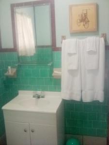 Un baño con lavabo y una pared de azulejos verdes. en BV Motel LLC, en Searchlight