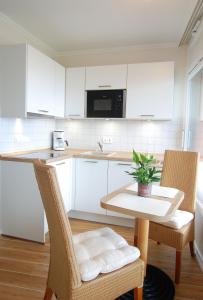 een keuken met witte kasten en een tafel en stoelen bij STRANDIDYLL, 58 - Typ A1S in Grömitz +17 foto's
