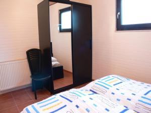 a bedroom with a mirror and a bed and a chair at Bungalow 451 in Tossens in Tossenserdeich