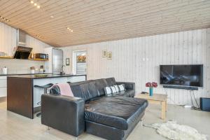 un salon avec un canapé en cuir et une cuisine dans l'établissement Beautiful And Well-Designed Holiday Home With Sea View, Spacious Terraces And Spa Just 200 Metres From The Child-Friendly Femmøller Beach And Close, à Ebeltoft