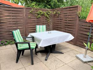 a white table and two green chairs on a patio at Haus Uschi - Ferienhaus in Cismar +3 photos